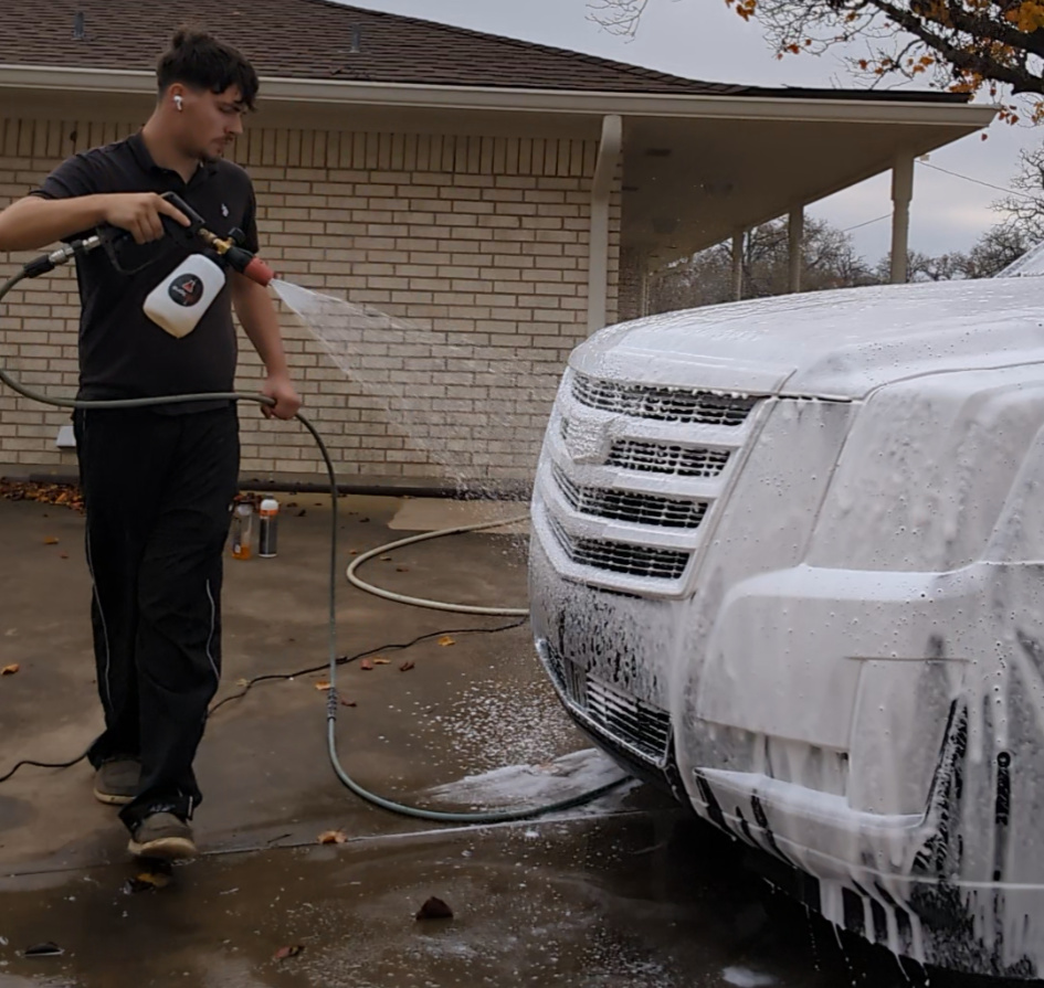 Timeless Detailing detailer foam-washing an SUV in a driveway